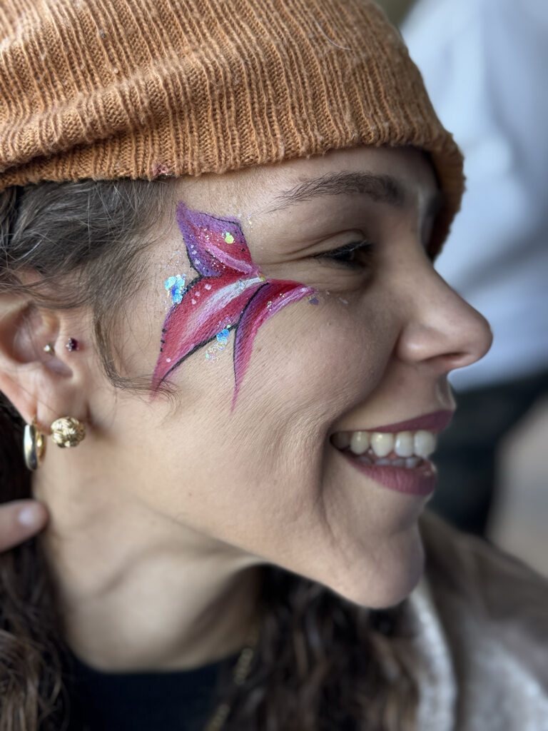 A woman with a small pink flower design on her face