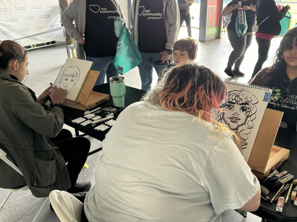 Two caricature artists at a baseball stadium drawing guests in different styles