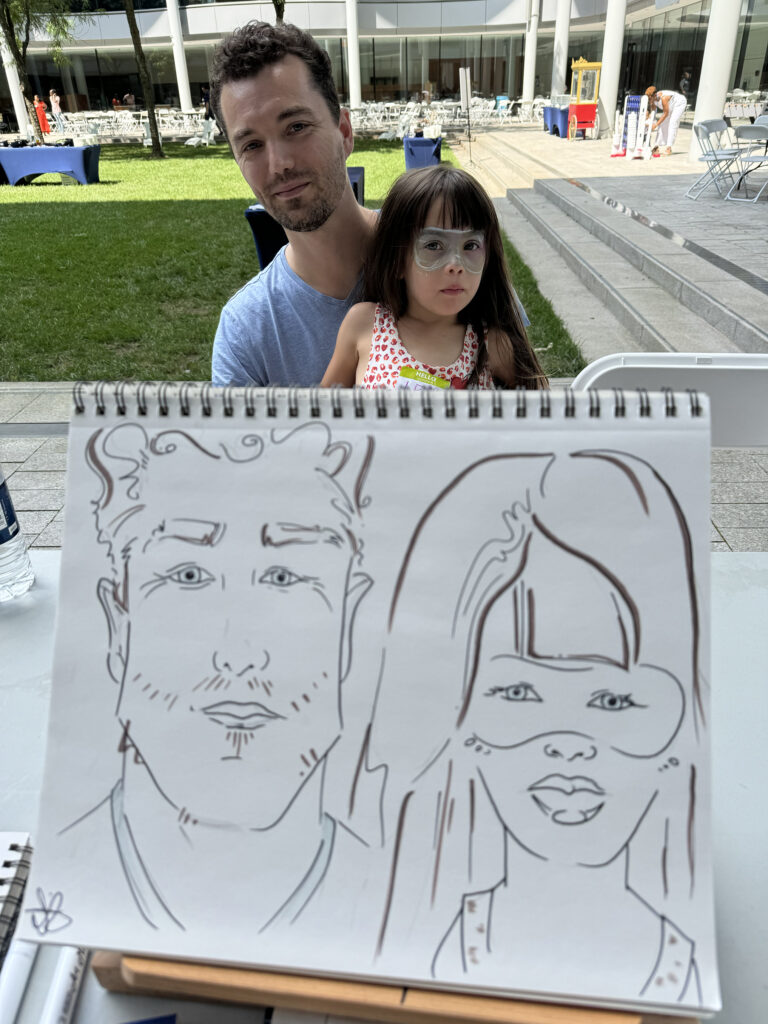 A family at an outdoor event having their caricatures drawn