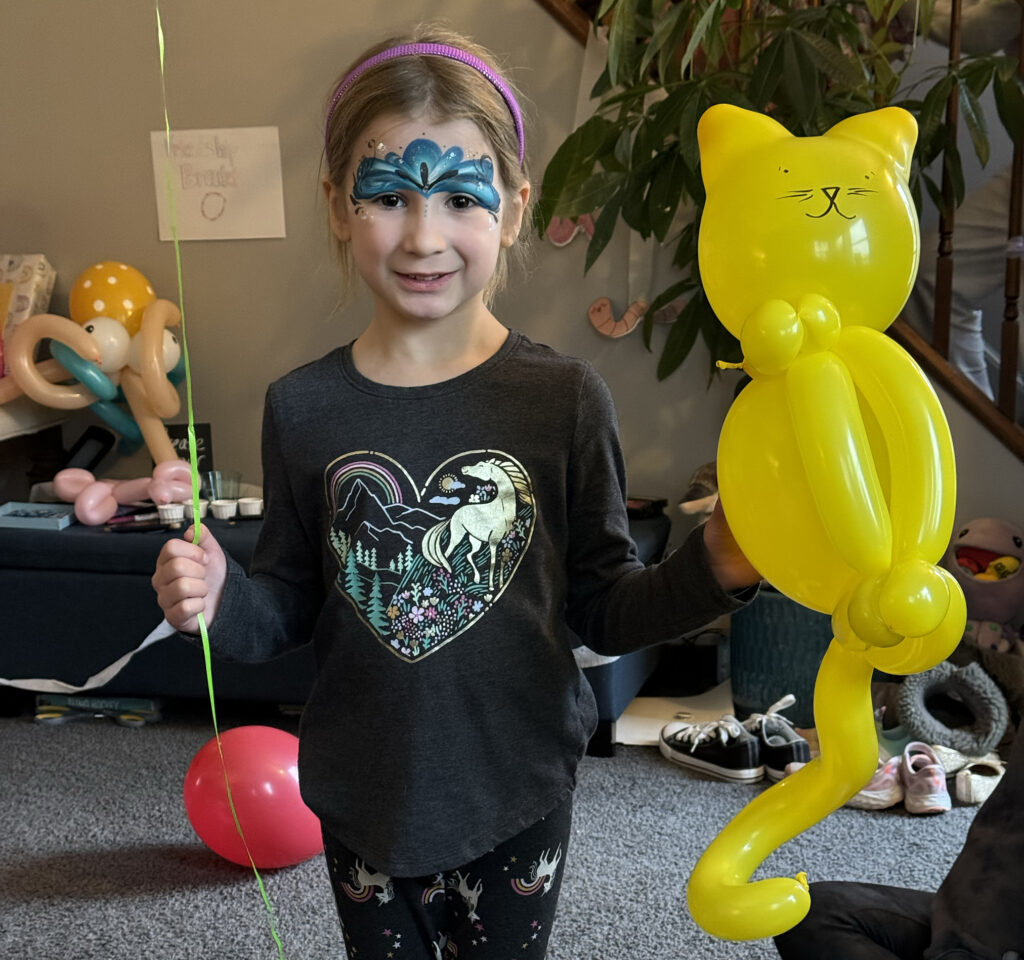 A girl holding two balloons with princess face painting