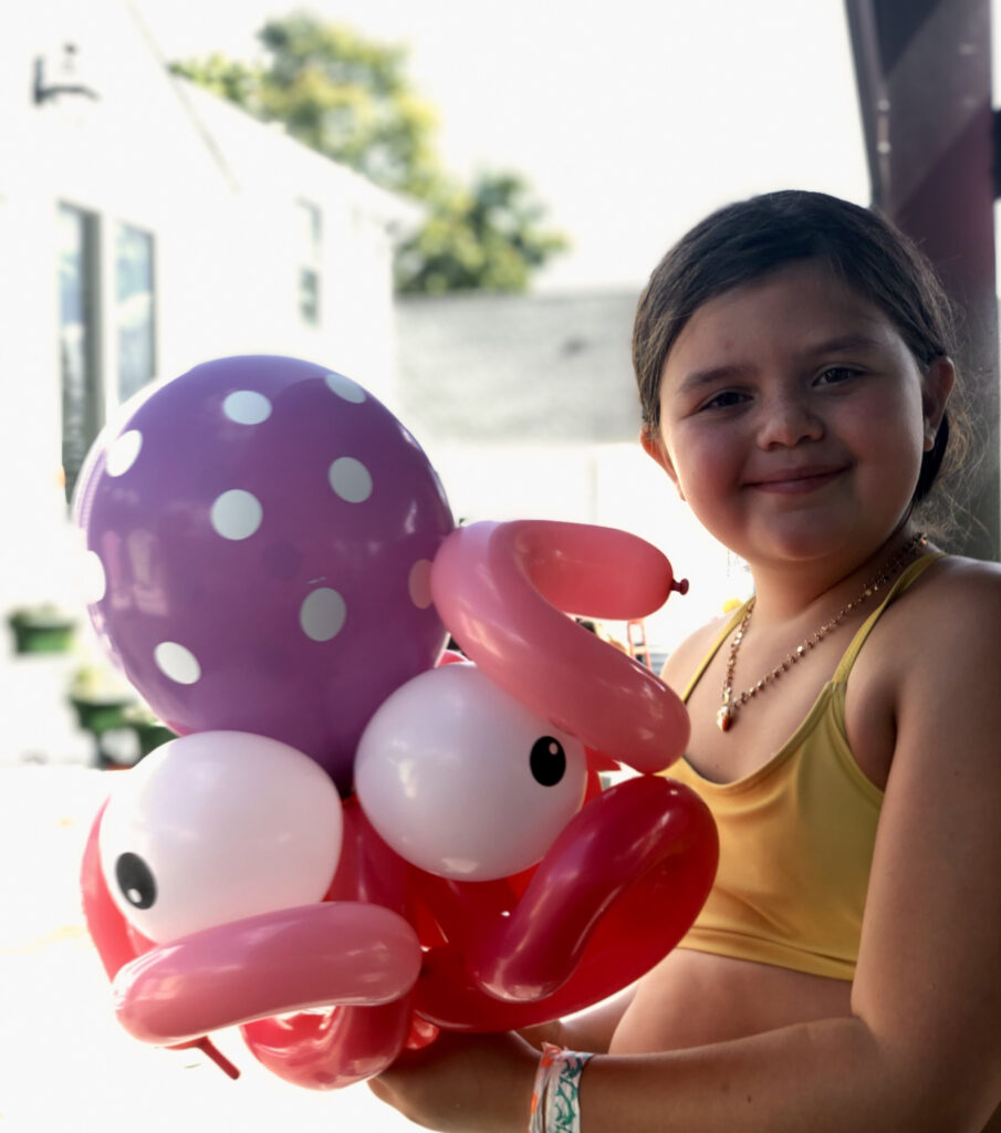 A girl holding a balloon octopus at a pool party in NH