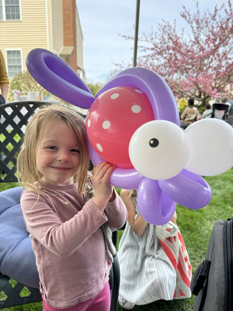 A child smiling at a backyard birthday in NH holding a large fish balloon animal