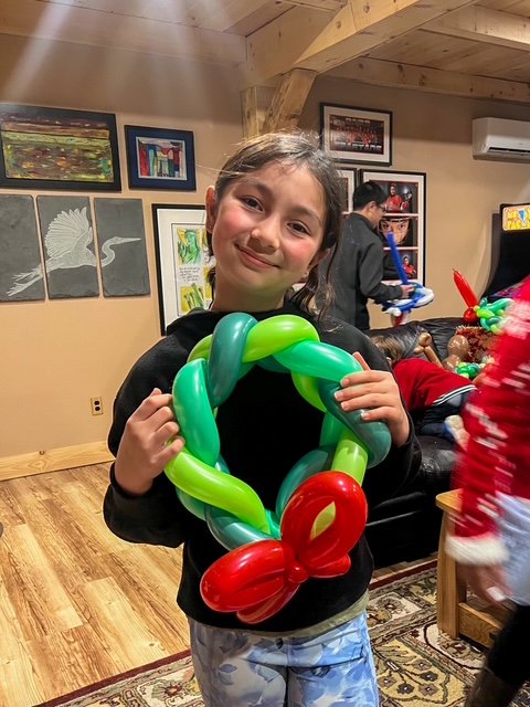 A girl holding a Christmas wreath twisted out of balloons